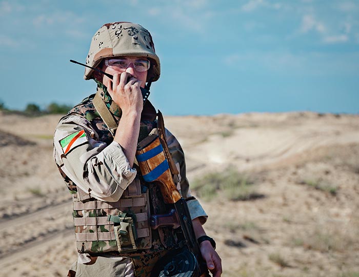 soldier in field talking on a radio